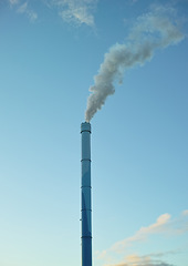 Image showing A factory chimney with smoke billowing into the air. Large amounts of steam or smoke billowing from an industrial smoke stack, adding to pollution and air contamination from big industrial industries