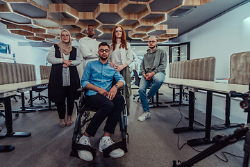 Image showing Young businessmen in a modern office extend a handshake to their business colleague in a wheelchair, showcasing inclusivity, support, and unity in the corporate environment.