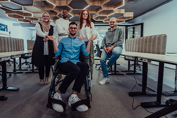 Image showing Young businessmen in a modern office extend a handshake to their business colleague in a wheelchair, showcasing inclusivity, support, and unity in the corporate environment.