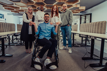 Image showing Young businessmen in a modern office extend a handshake to their business colleague in a wheelchair, showcasing inclusivity, support, and unity in the corporate environment.