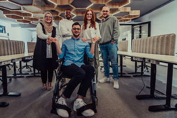 Image showing Young businessmen in a modern office extend a handshake to their business colleague in a wheelchair, showcasing inclusivity, support, and unity in the corporate environment.