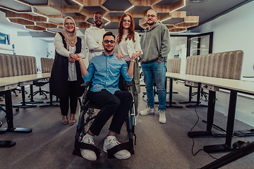 Image showing Young businessmen in a modern office extend a handshake to their business colleague in a wheelchair, showcasing inclusivity, support, and unity in the corporate environment.