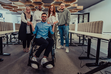 Image showing Young businessmen in a modern office extend a handshake to their business colleague in a wheelchair, showcasing inclusivity, support, and unity in the corporate environment.