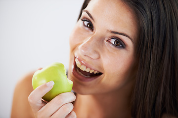 Image showing Woman, portrait and eating an apple, health and wellness in bite, nutrition and vitamins for vegan. Female person, fruit and organic or natural, smile and diet in breakfast, fresh and digestion