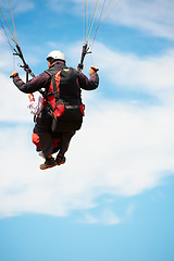 Image showing People, paragliding and freedom in sky, nature and extreme sport with back for fitness. Coach, partnership and person with adventure, helmet and fearless with backpack, parachute and jump with safety