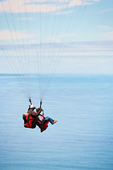 Image showing Sky, ocean and air with a couple in a parachute together for travel, freedom or adventure. Sea, summer or nature with a man and woman flying over the water while bonding on holiday or vacation