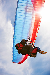 Image showing People, paragliding and freedom in sky, below or extreme sport for fitness in sunshine. Coach, partnership and person on adventure, lens flare or fearless with backpack, parachute or flight in clouds