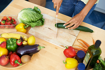 Image showing Woman, kitchen and cutting cucumber on wooden board above for healthy diet or vegetables at home. Top view of female person hands slicing natural organic vegetable for salad preparation at house