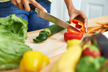 Image showing Woman, hands and cutting vegetables in kitchen on wooden board for healthy diet or vegetarian meal at home. Closeup of female person slicing natural organic red pepper for salad preparation at house