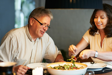 Image showing Mature couple, eating together at table with food and love in marriage with happiness in home. Lunch, old man and woman with smile, diet and salad for dinner in house with kindness, bonding and meal.