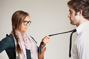 Image showing Flirty, grabbing tie and a couple on a studio background for love, attitude and a date. Romance, smile and a fun young woman with the attention of a man, flirting and romantic in a relationship