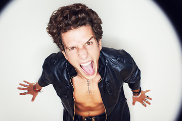 Image showing Man, tongue and leather jacket in studio portrait with spotlight, fashion and clothes by white background. Person, top view and rockstar for crazy face, shouting or jewelry for punk aesthetic