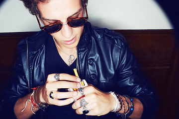 Image showing Man with cigarette in hand, grunge fashion and rockstar attitude on white background in spotlight. Cool punk style, rebel and smoking, confident and handsome male model in studio with sunglasses.