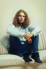 Image showing Man, relax on sofa and fashion model in portrait with casual clothes, curly hairstyle and cool style. Denim outfit, trendy and stylish with serious face, relax in a house with hair, young and gen z