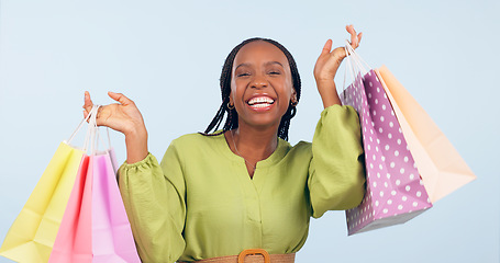 Image showing Black woman, shopping bag and retail in portrait with happiness for discount on fashion giveaway in studio. Choice, happy and commerce with smile for sale, service and gift on blue background