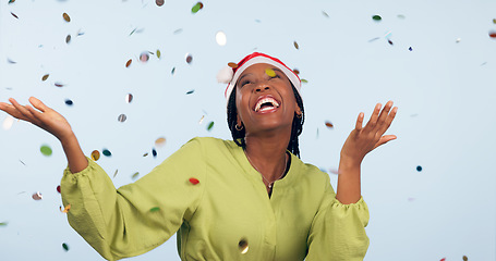 Image showing Christmas, confetti and black woman with celebration, party or happiness on blue studio background. African person, girl or model with glitter, excited or event with joy, Xmas or winning with holiday