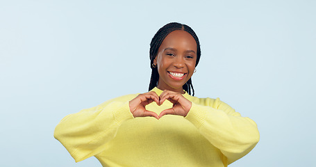 Image showing Portrait, heart and hands of black woman in studio for love, kindness or charity donation on blue background. Happy model show finger sign of hope, care or thank you emoji for support, review or vote