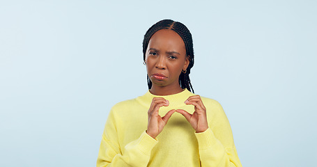 Image showing Woman, portrait and hands of broken heart in studio for sad breakup, depression and lonely emotion on blue background. Unhappy african model show heartbreak emoji for divorce, trauma and pain of love