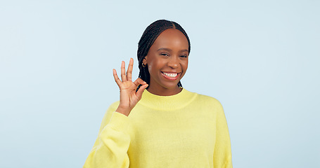 Image showing Ok, hands and portrait of woman in studio for certified review, winning feedback or vote yes on blue background. Happy african model show sign of excellence for success, like emoji or icon of support