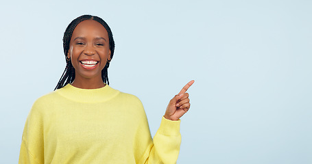 Image showing Pointing, smile and black woman with opportunity, portrait and announcement on a blue studio background. African person, model or girl with hand gesture, mockup space and choice with decision or news