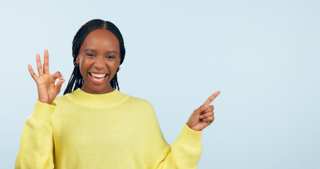Image showing Pointing, portrait and black woman with opportunity, ok sign and announcement on a blue studio background. African person, model and girl with hand gesture, mockup space and agreement with feedback