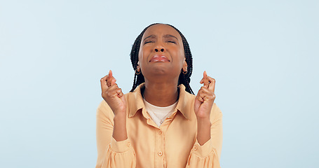 Image showing Nervous, woman and hope with fingers crossed in studio for lucky news, feedback and waiting with anxiety on blue background. African model, worry and stress with hand sign for wish, praying and emoji