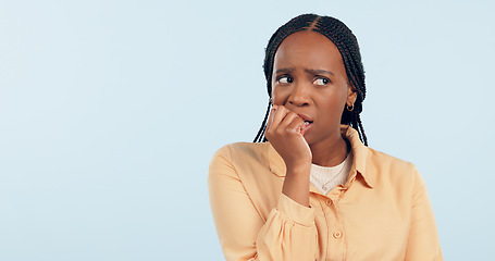 Image showing Woman, anxiety and biting nails in studio for stress, bad habit and thinking of horror on blue background. Nervous african model chewing fingers for terror, worry and scared of fear with mockup space