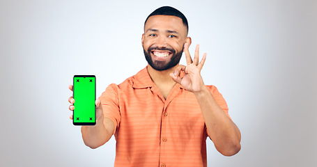 Image showing Man, portrait and ok for phone with green screen, space or agreement in studio on white background. Happy model, smartphone or yes emoji for certified newsletter, promotion or advertising information