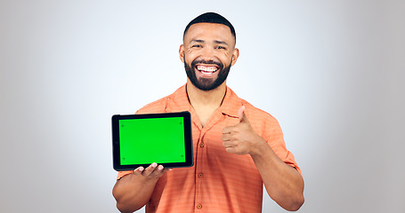 Image showing Portrait, man and thumbs up for tablet with green screen, space or agreement of deal in studio on white background. Happy model, digital marketing and like emoji for newsletter, promotion and support