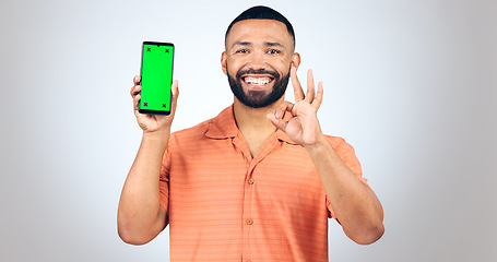 Image showing Portrait, man and okay for phone with green screen, space and agreement sign in studio on white background. Happy model, smartphone and yes emoji for certified news, promotion or advertising feedback