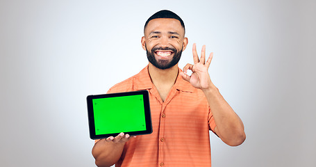 Image showing Portrait, man and ok for tablet with green screen, space or advertising agreement in studio on white background. Happy model, digital marketing and yes emoji for promotion, sign up deal or newsletter