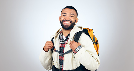 Image showing Man, portrait and hiking in studio with backpack and smile from travel and freedom with adventure. Camping, fitness and grey background and walking with trekking camper gear for vacation and holiday