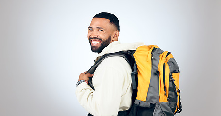 Image showing Man, happy portrait and hiking in studio with backpack and smile from travel and freedom with adventure. Camping, fitness and grey background and walking with trekking gear for vacation and holiday