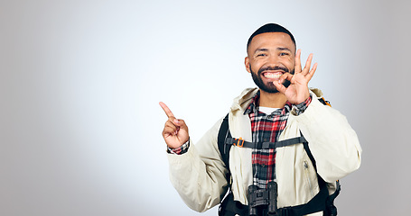 Image showing Hiking portrait, pointing and happy man okay sign for studio promotion, discount deal offer or travel vacation agreement. Ok emoji icon, mockup space and studio hiker backpacking on white background