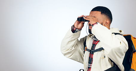 Image showing Man, binoculars and backpack in studio with mockup space and safari from travel and freedom with adventure. Camping, fitness and grey background and walking with trekking holiday gear for vacation