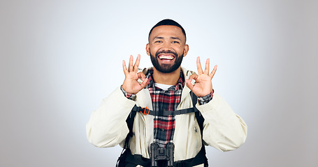 Image showing Perfect sign, hiker and portrait of man in a studio with a backpack for hiking adventure. Happy, smile and young male person from Mexico with ok hand gesture for camping isolated by gray background.