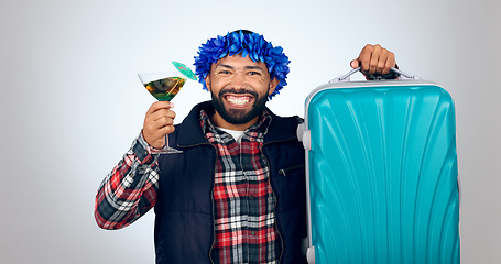 Image showing Portrait, cocktail and suitcase for travel with a man in studio on a gray background for holiday or vacation. Smile, alcohol and luggage with a happy young tourist drinking in celebration of a trip