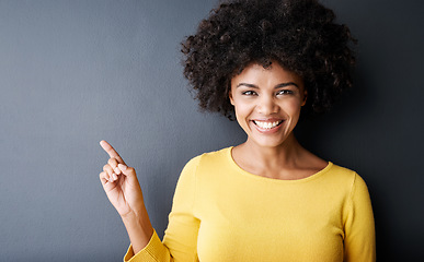 Image showing Black woman, pointing and happy portrait in studio, mockup and gray background with announcement information. Hand, sign or face of person with opinion, advice or positive choice and gesture to promo