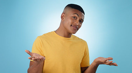 Image showing Confused, portrait and man shrug in studio with why hands on blue background space. Doubt, face and model with dont know emoji for choice, decision or palm scale, questions or asking body language