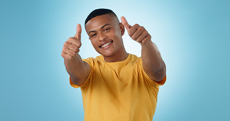 Image showing Thumbs up, portrait and man in studio for success, winning deal and celebrate achievement on blue background. Happy model, emoji and like sign for feedback, voting yes and thank you for excellence