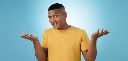 Image showing Confused, portrait and man in studio shrug with emoji hands or asking body language on blue background. Why, face and male model with palm scale questions, doubt or comparison, balance or dont know