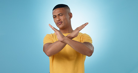 Image showing Man, cross and hands for no, portrait or studio with frustrated face for choice by blue background. Person, sign and icon for stop, warning and attention with block emoji, decline or annoyed for fail