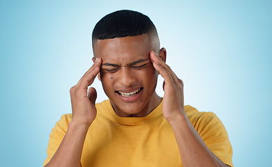 Image showing Headache, stress and man in studio with anxiety, burnout or frustrated by brain fog on blue background. Vertigo, face and male model with temple massage for pain, migraine or fear of tax or audit