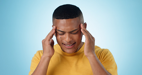 Image showing Man, pain and headache in studio of stress, challenge or fatigue of mental health on blue background. Frustrated model dizzy with crisis of anxiety, brain fog or tired of migraine, vertigo or burnout