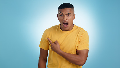 Image showing Pointing, shock and portrait of man in a studio with mockup for marketing, advertising or promotion. Surprise, wow and young male person with a show hand gesture isolated by blue background.