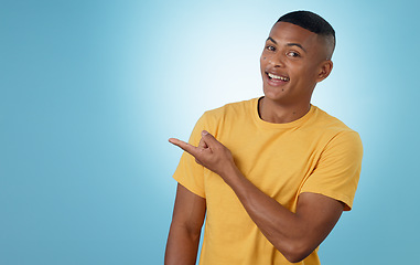 Image showing Man, student pointing and presentation for education, learning or college news and information in studio. Portrait of a young person with university guide, advice and mockup on a blue background