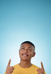 Image showing Man, face and pointing up to space in studio for advertising choice, decision or information about us on blue background. Happy model, thinking and show presentation of mockup, ideas and announcement