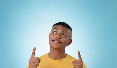 Image showing Man, space and pointing up in studio for advertising choice, decision and information about us on blue background. Face, model and thinking to show presentation of mockup, promotion and announcement