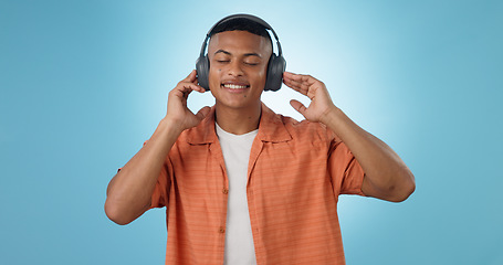 Image showing Music, calm man and dancing with headphones and studio with radio and audio app with blue background. Tech, smile and sound with relax African male person with web media streaming and hearing a song