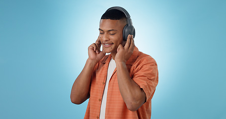 Image showing Music, man and happy with headphones and studio with radio and audio app with blue background. Tech, smile and sound with relax African male person with web media streaming and hearing a song